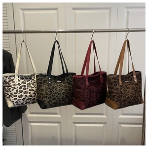 Detail view of leopard print tote bags in four colors with leather straps and metal accents