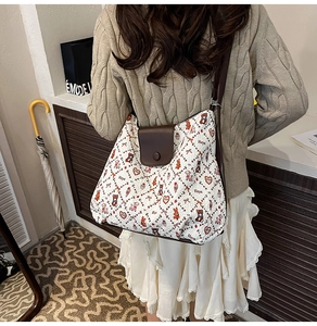 Close-up of quilted tote bag with bear print and leather strap shown on a model