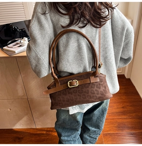 Detailed close-up of brown leopard print suede handbag with metallic buckle and slim strap