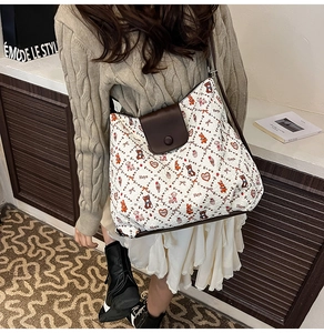 Detail of white tote bag with bear print and brown leather flap worn by model