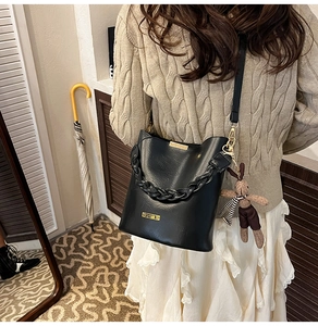 Detail of black leather bucket bag with braided handle and cute bunny charm pendant