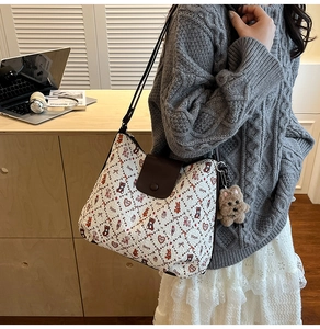 Detail of a white patterned shoulder bag with a cute plush puppy pendant on the side
