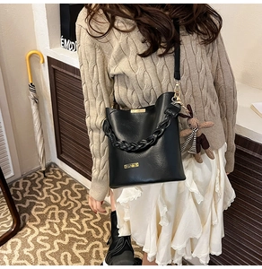 Detail of black leather bucket bag with woven handle and cute rabbit charm accessory
