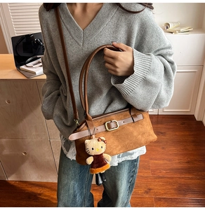 Detail view of vintage brown suede shoulder bag with leather straps and metal buckle
