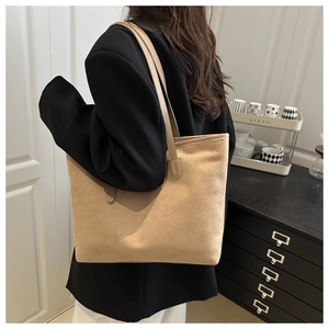 Minimalist camel suede tote bag shown on shoulder in a stylish home setting