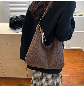 Detail of hobo bag featuring leopard print pattern and vintage wooden bead charm