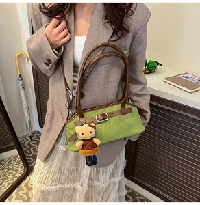Detail of green suede shoulder bag with brown leather handles and Hello Kitty plush charm
