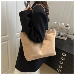 Detail of soft apricot suede tote bag worn by a model in a minimalist modern setting
