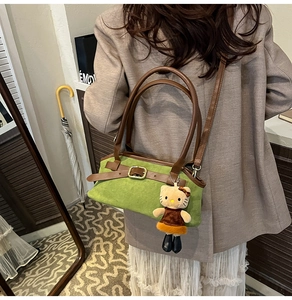Detail of retro green suede shoulder bag with brown leather strap and cute plush charm