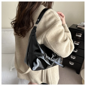 Detail of glossy black crescent shoulder bag with silver eyelet belt buckle strap