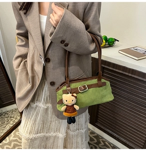 Green suede hobo bag with brown leather handles and decorative metallic buckle strap