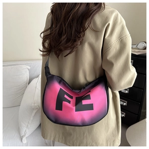 Detail of crescent crossbody bag with pink-black gradient finish and FE logo on a model