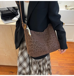 Close-up of leopard print tote bag with wooden bead charm in a cozy office setting