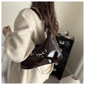 Détails de la boucle argentée et des œillets sur le sac à bandoulière marron brillant