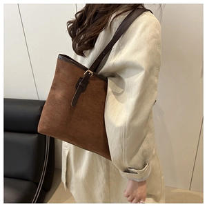 Close-up of brown suede tote bag with leather strap and buckle on model shoulder