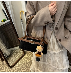 Detail of retro black suede tote bag with brown leather trim and Hello Kitty charm