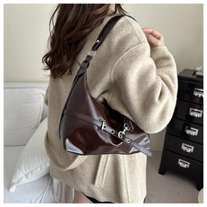 Détail du sac hobo marron foncé brillant avec boucle métallique sur la bandoulière