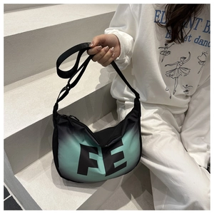 Detail showing crescent-shaped black to mint green gradient bag with FE letter print