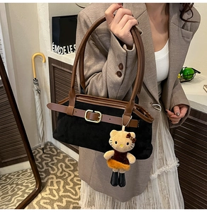Detail of vintage black suede shoulder bag with brown leather strap and plush cat charm