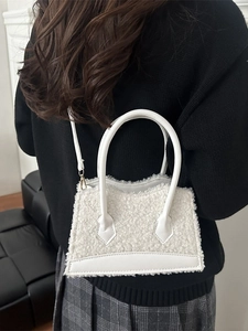 Chic white faux shearling tote bag with leather trim worn by a model in a minimalist style