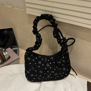 Black corduroy hobo bag with white bow heart print and gathered strap on desk