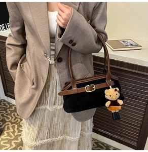 Detail of vintage black and brown shoulder bag with gold buckle and plush charm