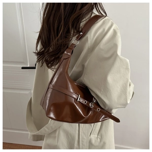 Detail of dark brown glossy leather shoulder bag with silver buckle and sleek strap