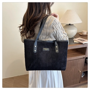 Achteraanzicht van zwarte corduroy shopper met leren riemen gedragen door model