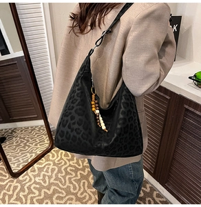 Detail of leopard print hobo bag with wide strap and colorful beaded tassel charm