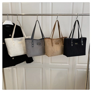 Details van vier corduroy tote bags in beige, grijs, kaki en zwart hangend aan een rek