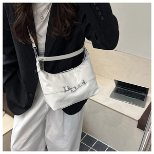 White glossy shoulder bag with minimalist buckle and adjustable strap shown on model