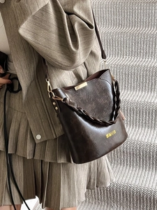 Retro dark brown bucket bag with gold hardware worn by a model in a minimal urban setting