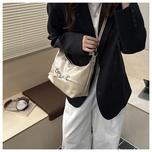 Close-up of beige patent leather dumpling bag with silver buckles and strap detail