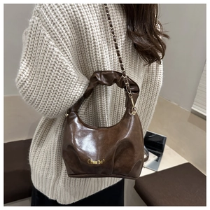 Detailed view of dark brown pleated hobo bag with golden chain and glossy finish