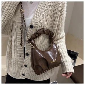 Detail of soft brown pleated dumpling bag with golden chain strap and leather handle