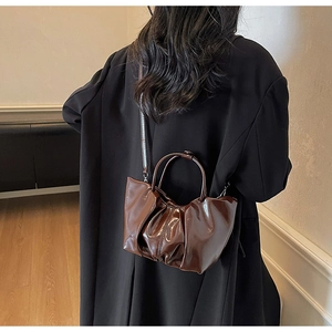 Detail of the dark brown pleated tote bag with a high-gloss finish for a modern look