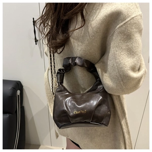 Detail of dark brown ruched handbag with golden chain strap and leather handle