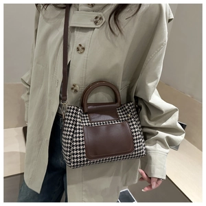 Detail of a vintage houndstooth handbag with brown leather accents on a casual model