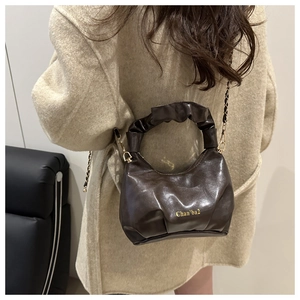 Detail of vintage brown pleated mini crossbody bag with gold chain strap on model