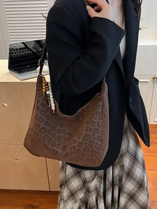 Vintage leopard print shoulder bag with beaded charm on a stylish model in a suit