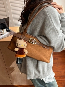 Retro dark brown suede underarm shoulder bag with Hello Kitty charm in lifestyle setting