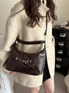 Deep brown retro underarm bag with metal buckle detail shown on a model in wool coat