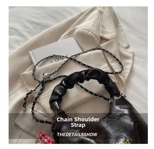 Detail view of dark brown ruched leather handbag with a metallic silver chain strap