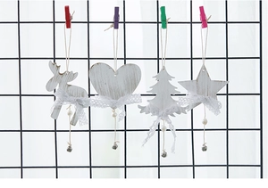 Detailed close-up of white wooden Christmas ornaments with lace bows and small metal bells