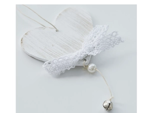 Close-up of white wooden heart ornament with lace bow, pearl and bell detail