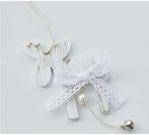 Close-up of white wooden reindeer ornament with lace bow, bell and pearl detail