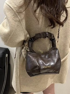Retro brown PU leather handbag with pleated handle and gold chain strap shown on model coat