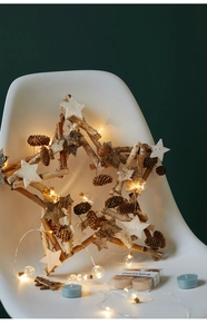 Close-up of star-shaped holiday wreath with pine cones, wood stars and warm LED lights