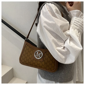 Close-up of premium brown leather underarm bag with M-letter print and metallic logo
