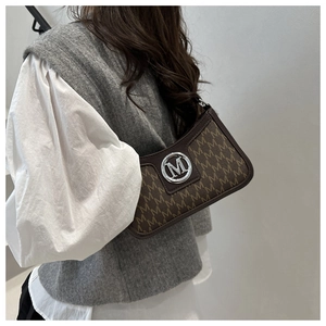Detail of vintage brown shoulder bag with monogram print and round silver M logo buckle